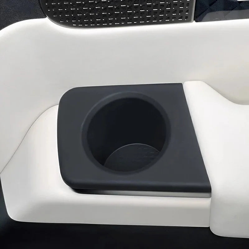 Black matte textured cup holder integrated into white premium car interior trim.