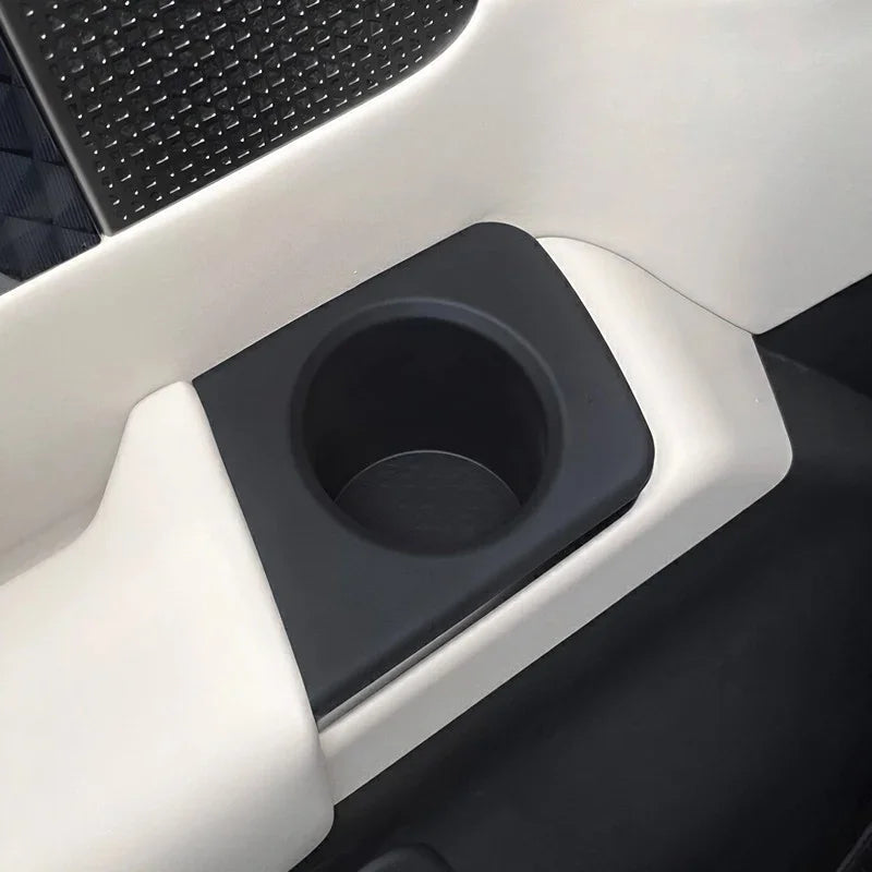 Black matte car door cup holder integrated into white interior trim.