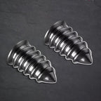 Two polished chrome metallic decorative screw-shaped ornaments on a dark textured surface.