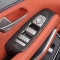 Carbon fiber texture door trim panel with silver control switches on orange leather interior.