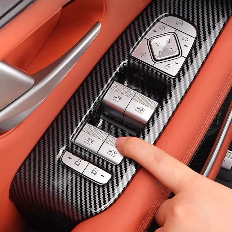 Carbon fiber texture door panel trim with silver window control switches on orange leather interior.