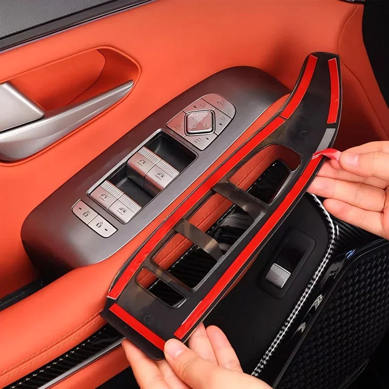 Black carbon fiber texture door trim protector with red protective film being applied to car interior.