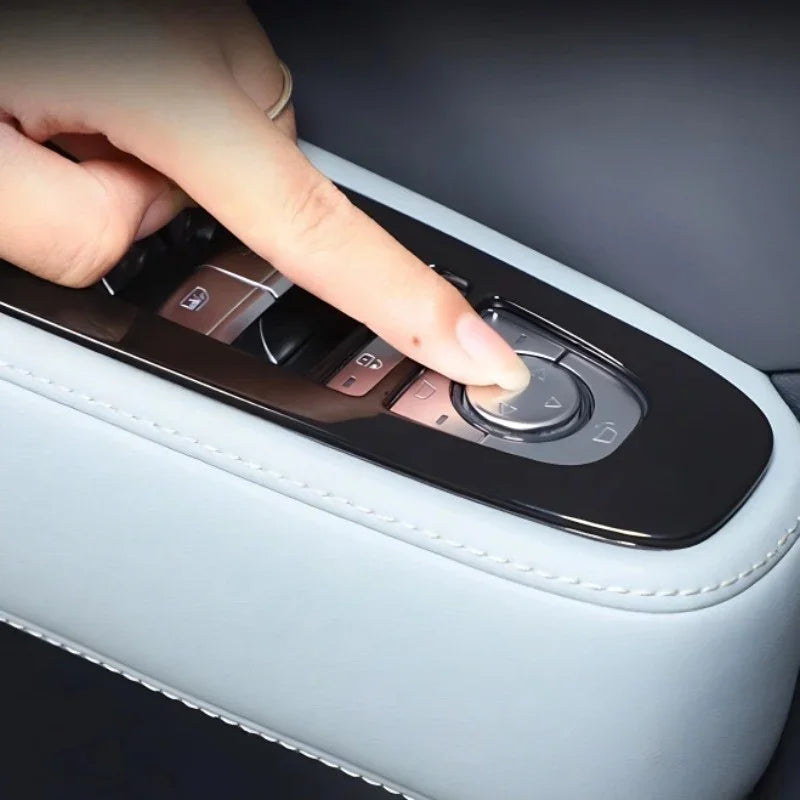 A hand operating the black glossy control panel on a light grey leather car center console.