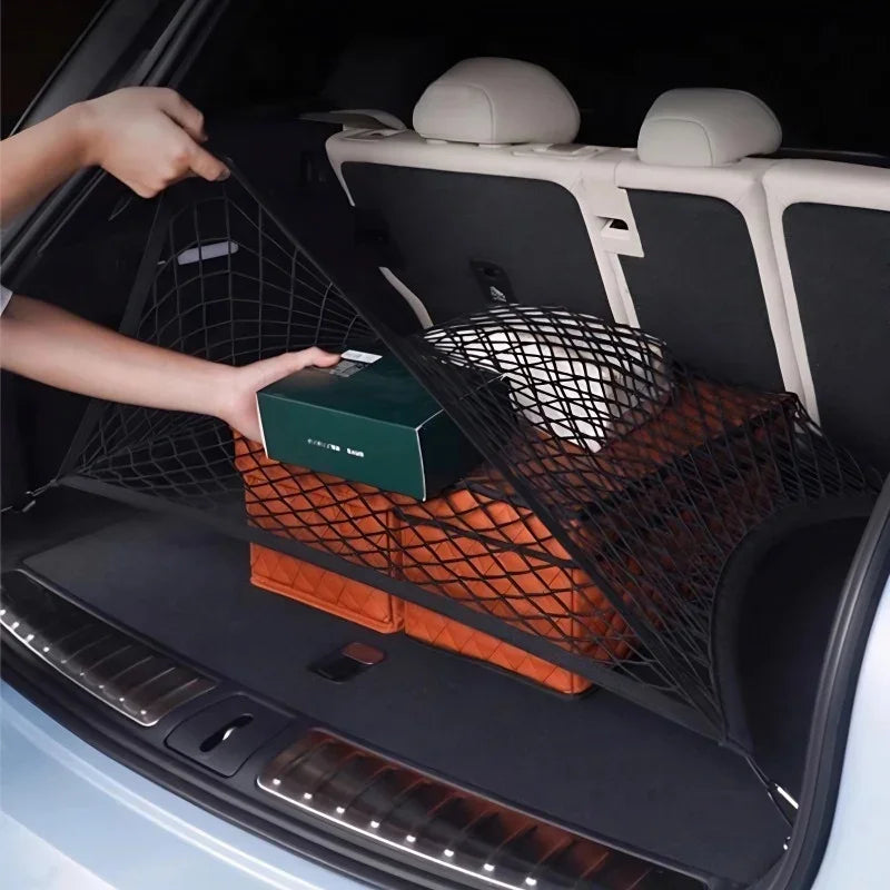 Black elastic cargo net securing boxes in a car trunk for organized storage.
