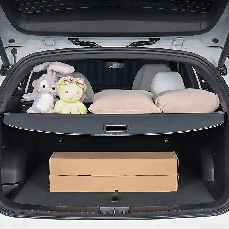 Black custom-fit trunk mat protecting the car cargo area with soft beige pillows and plush toys.