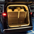 Warm LED light strip illuminating the brown interior of a car trunk with beige leather seats.