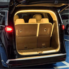 Warm LED light strip illuminating the brown interior of a car trunk with beige leather seats.