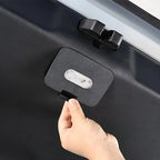 Hand installing a black matte plastic trunk light cover with integrated LED on a vehicle.