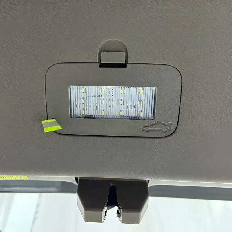 Interior car dome light with LED bulbs mounted on a grey ceiling trim.