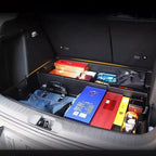 Black custom-fit trunk organizer tray with various items stored in a car cargo area.