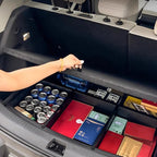 Black custom-fit trunk organizer box containing canned drinks and various packaged goods.