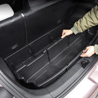 Person installing a black, durable plastic custom-fit cargo liner in a vehicle trunk.