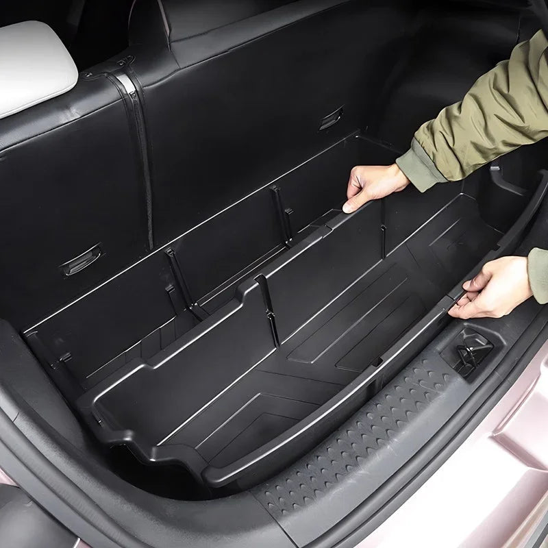 Person installing a black, durable plastic custom-fit cargo liner in a vehicle trunk.