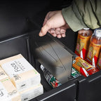 Black matte car organizer compartment with a sliding lid storing beverages and tissues.