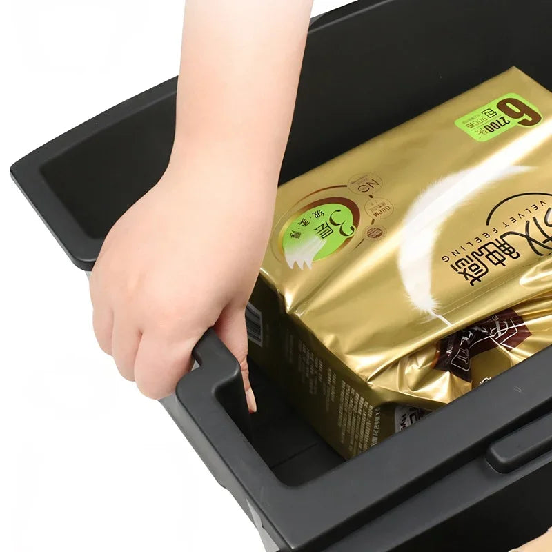 A hand reaching into a black durable plastic storage bin containing gold-packaged products.