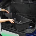 Professional black durable plastic cargo organizer being placed in a car trunk.