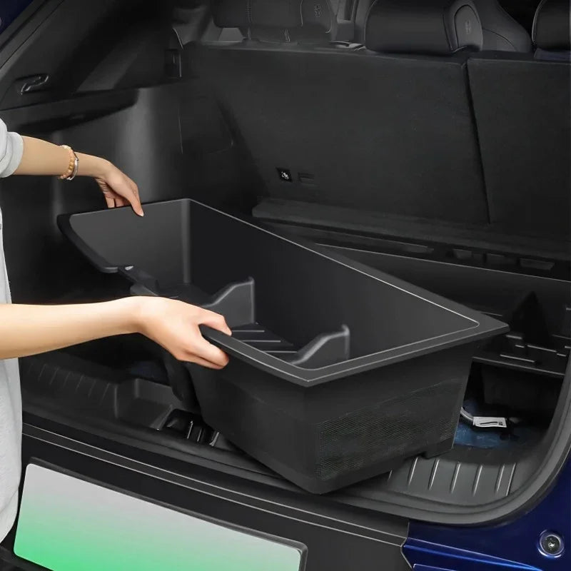 Professional black durable plastic cargo organizer being placed in a car trunk.