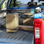 Black heavy-duty mesh cargo net securing cardboard boxes in a blue truck bed.
