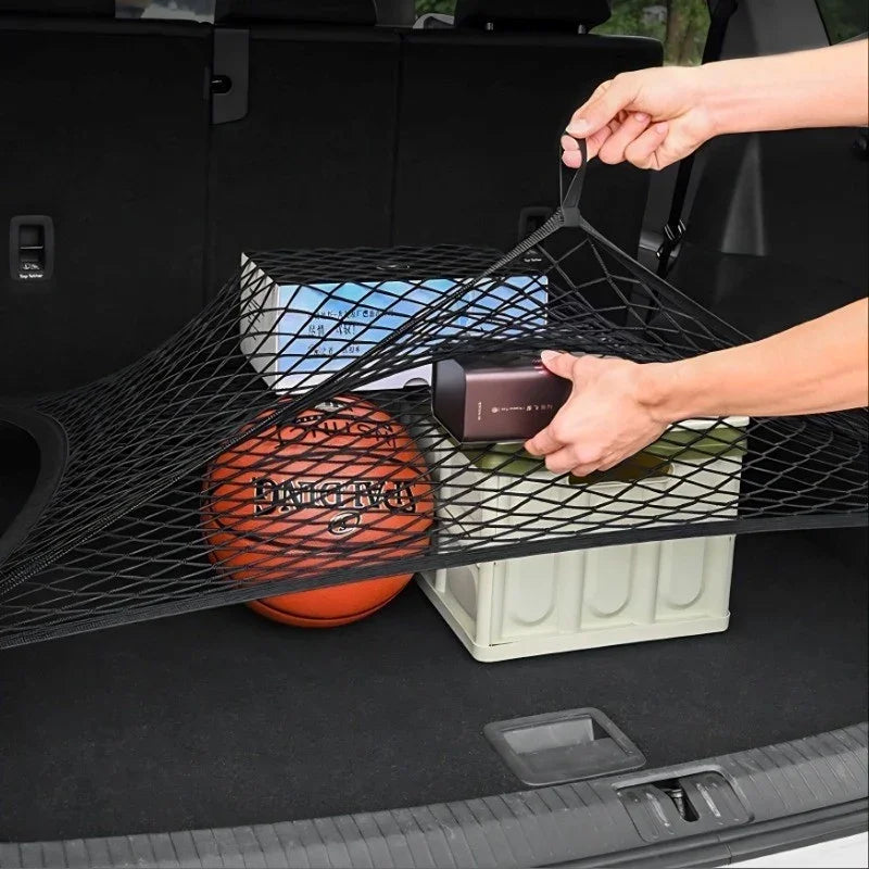 Black mesh cargo net securing a basketball and storage box in a car trunk.