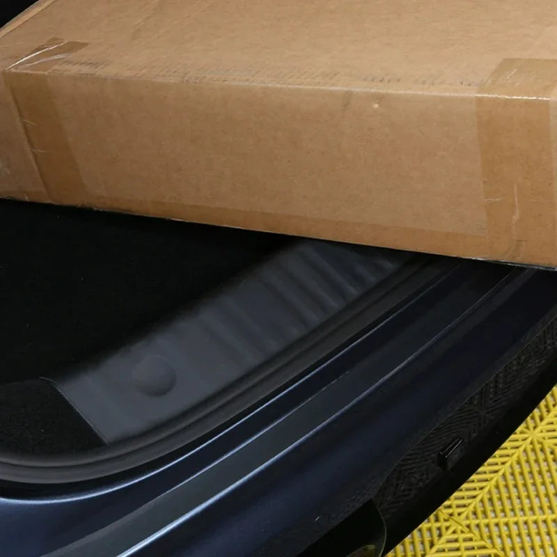 Durable black rubber protective trunk sill protector installed on a dark blue car bumper.