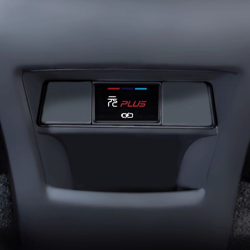 Close-up of a black matte plastic interior car console with a backlit PLUS control button.