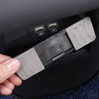 Grey plastic car interior accessory with PLUS marking, featuring a textured finish.