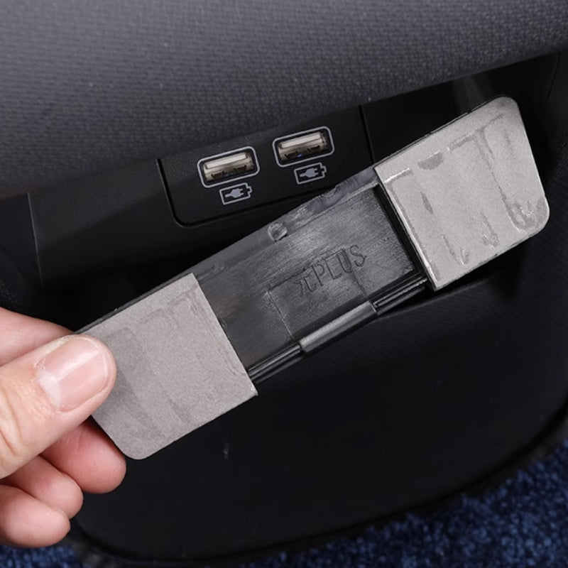 Grey plastic car interior accessory with PLUS marking, featuring a textured finish.