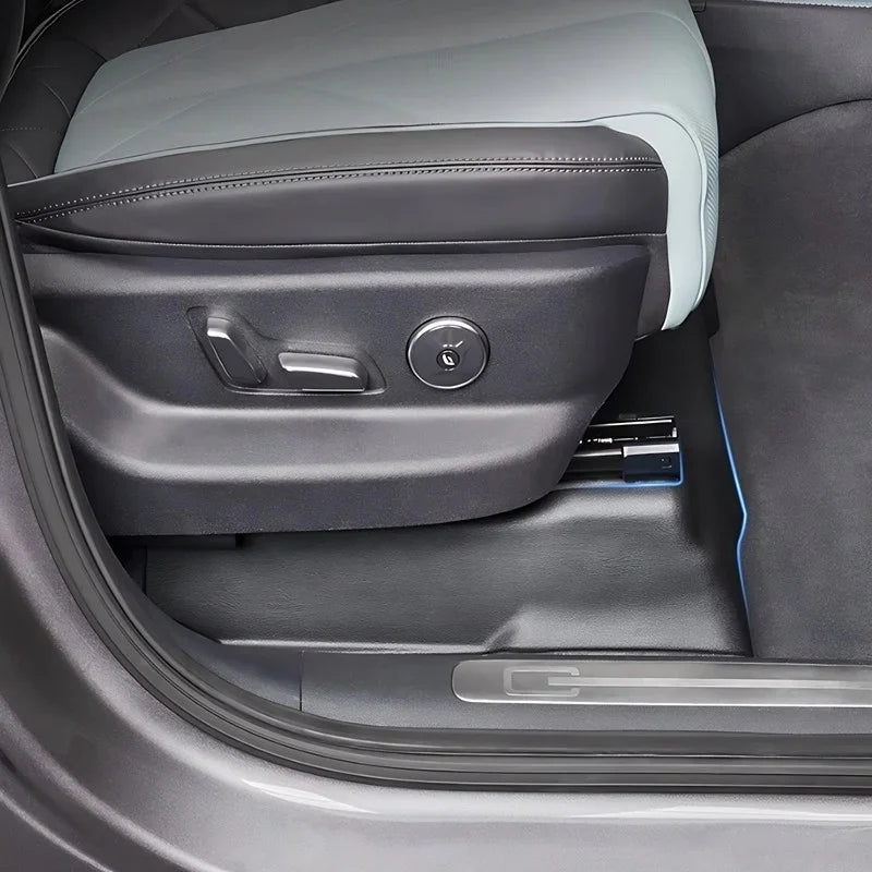 Black leather car seat side trim with grey stitching and integrated electronic controls.