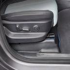 Black leather car seat side trim with grey stitching and integrated electronic controls.