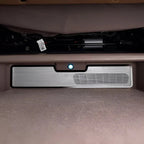 Silver brushed metal car interior trim panel with integrated air vent and indicator light.