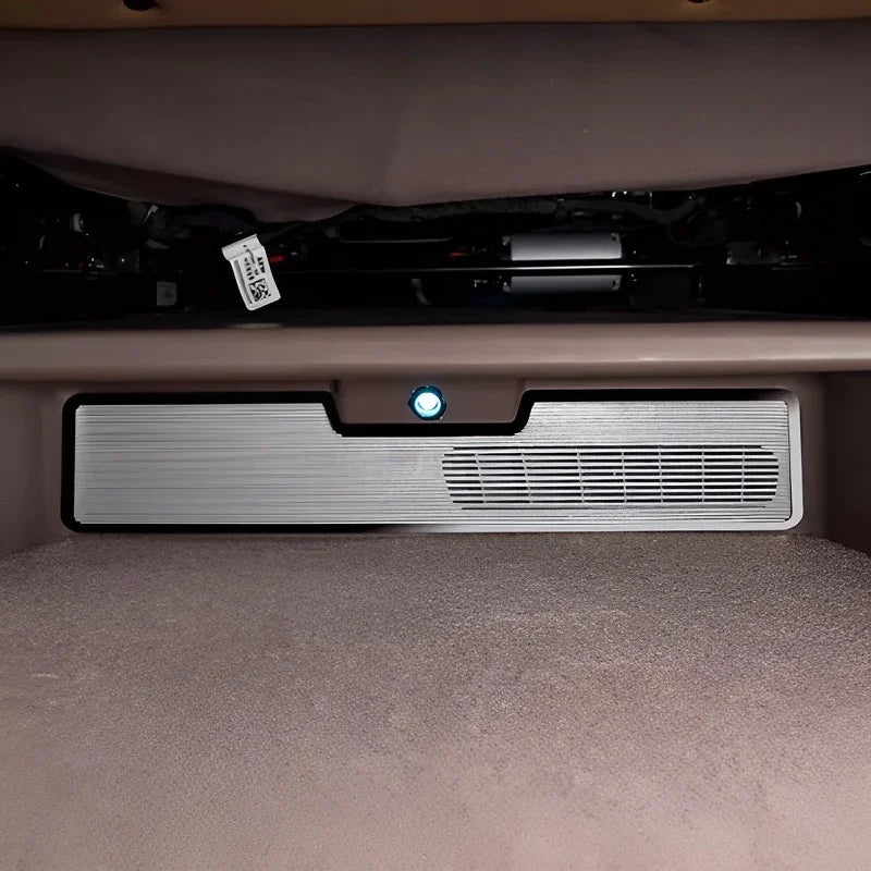 Silver brushed metal car interior trim panel with integrated air vent and indicator light.