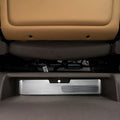 Silver brushed metal kick mat protector installed on the underside of a tan car seat.
