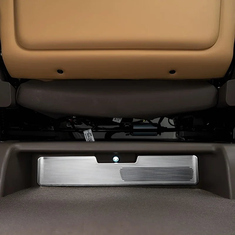 Silver brushed metal kick mat protector installed on the underside of a tan car seat.