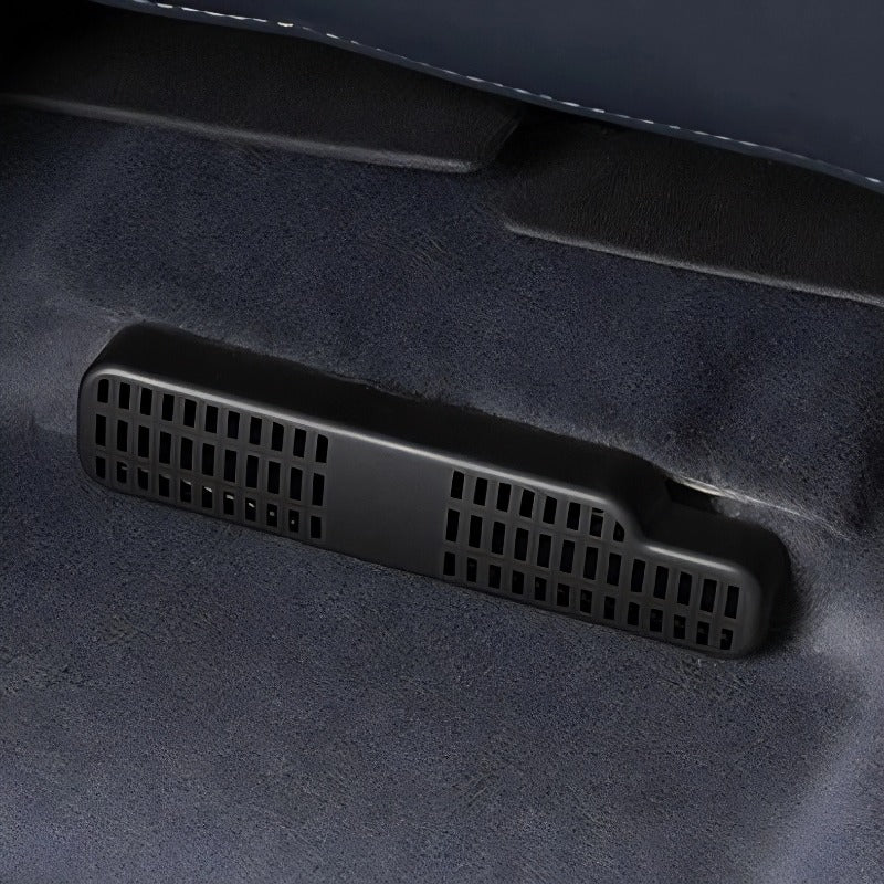 Close-up of a black matte plastic ventilation grill installed on a grey suede car interior.