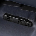 Close-up of a black matte plastic ventilation grill installed on a grey suede car interior.