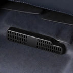 Close-up of a black matte plastic ventilation grill installed on a grey suede car interior.