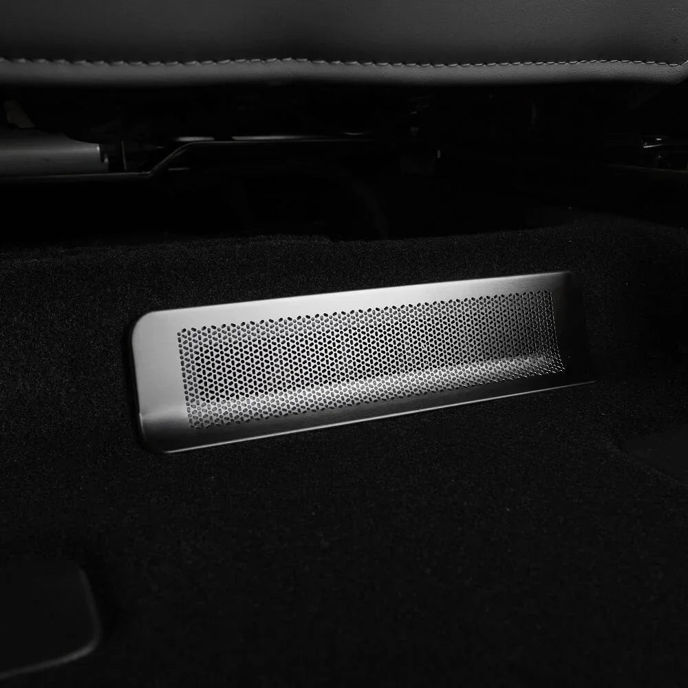 Silver perforated metal floor vent plate installed on black car carpeting.