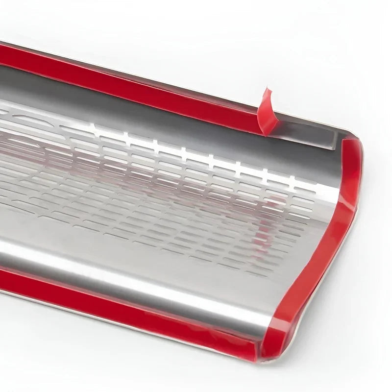 Red-trimmed stainless steel tray with a perforated design for vehicle protection.