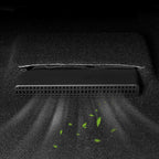 Black plastic under-seat car vacuum cleaner removing debris from a dark grey carpet.