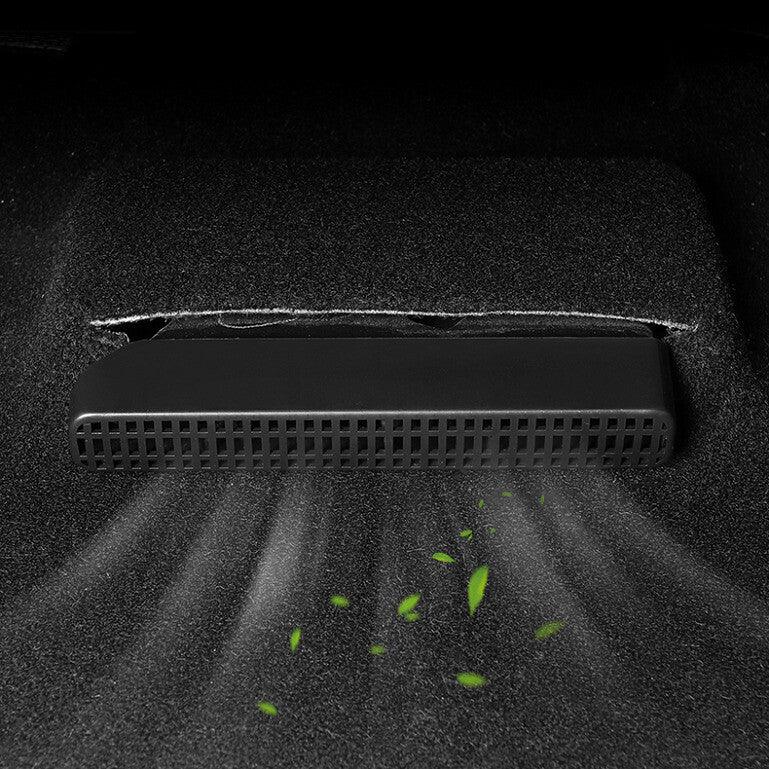 Black plastic under-seat car vacuum cleaner removing debris from a dark grey carpet.