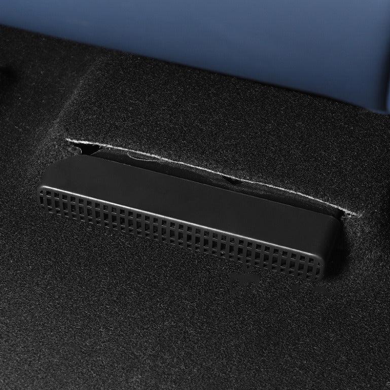 Black textured plastic vent cover integrated into dark grey automotive carpet flooring.
