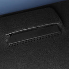 Close-up of a black perforated plastic vent integrated into a grey carpeted car interior.