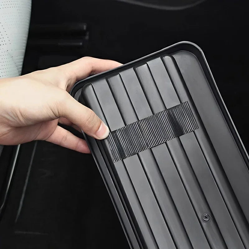Close-up of a hand touching a black durable ribbed rubber car floor mat with anti-slip texture.