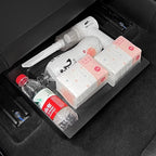 Black waterproof trunk organizer tray holding water bottles and pink tissue packs in a car trunk.