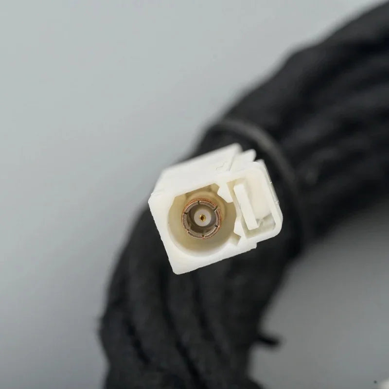 Close-up of a white plastic electrical connector with a copper terminal on a black wiring harness.