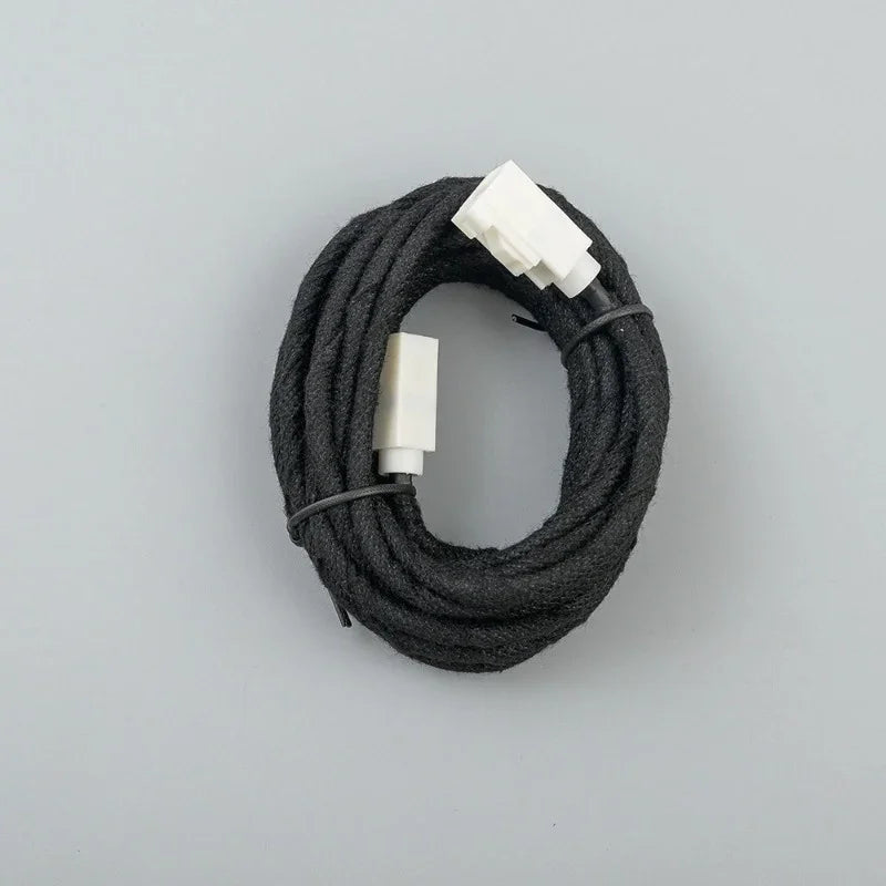 Coiled black fabric-wrapped automotive wiring harness with white plastic connectors