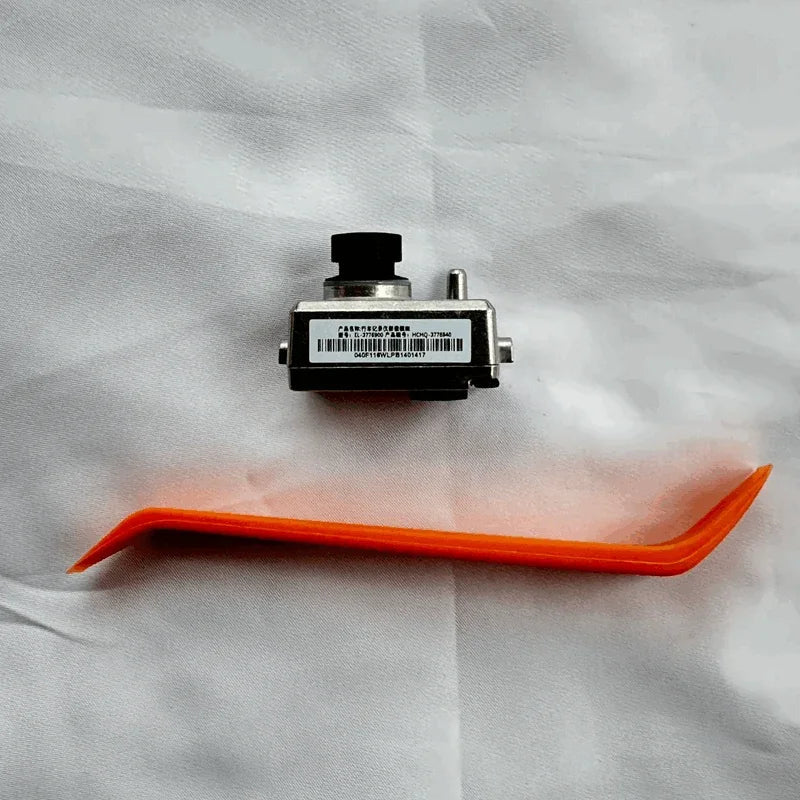 Silver metal automotive sensor component with black cap and orange plastic pry tool.
