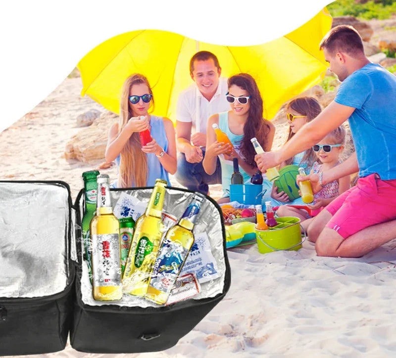 Black insulated picnic cooler bag filled with chilled glass beverage bottles on a sunny beach.