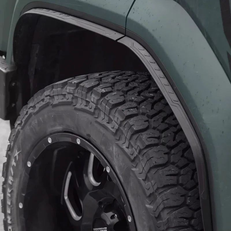 Rugged black matte fender flares installed on a dark green off-road vehicle tire.