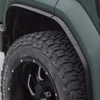 Rugged black matte fender flares installed on a dark green off-road vehicle tire.